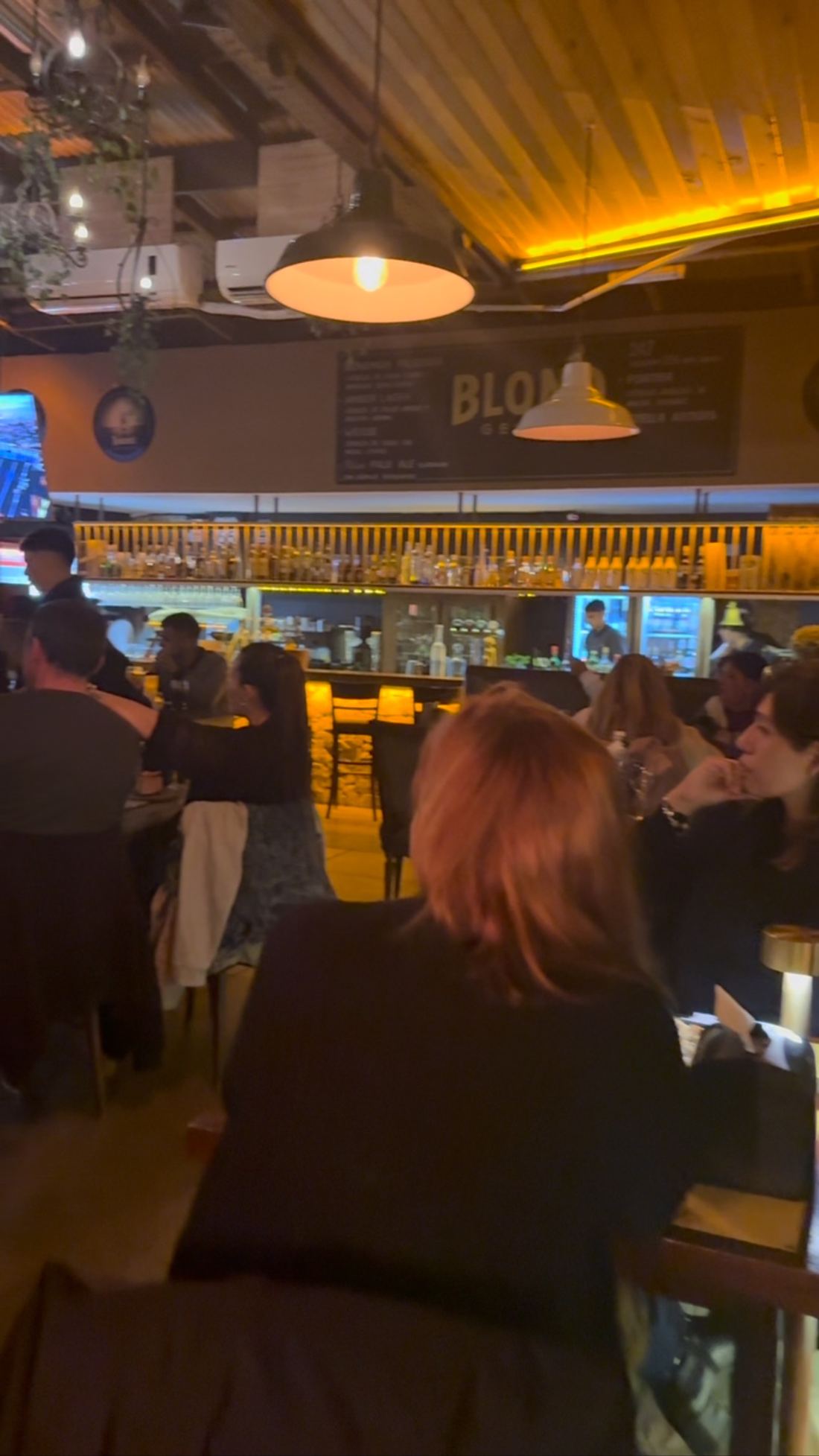 Salón de BLOND con la barra iluminada y mesas llenas